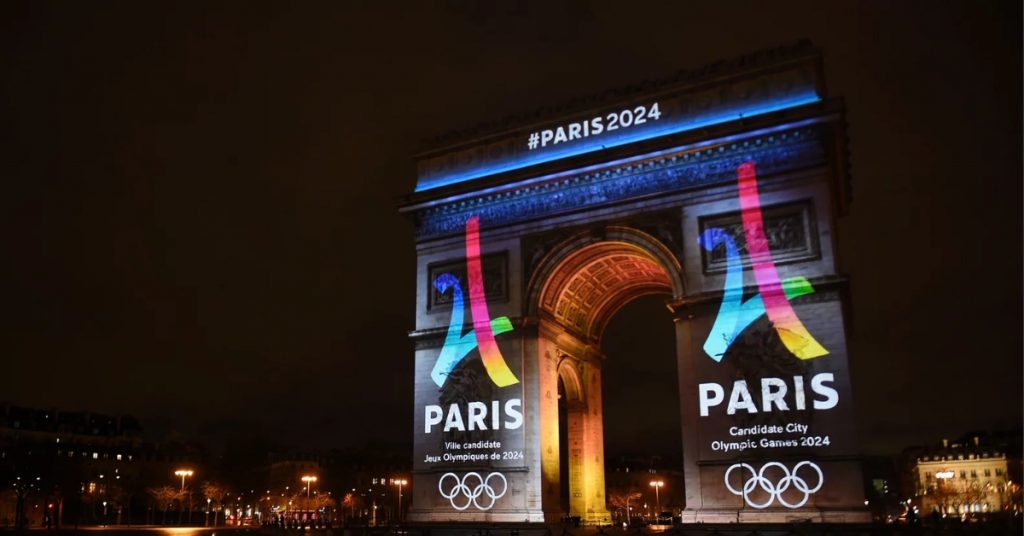 Arc de Triomphe lit up with the words Paris 2024 and the Olympic Symbol