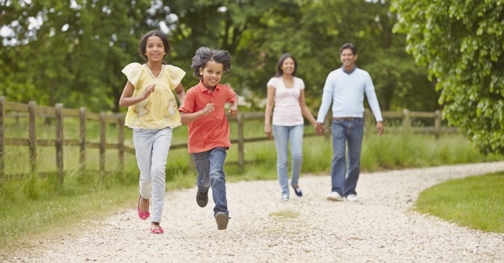 Family of mother, father and son and daughter joyfully walking through the countryside