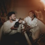Couple pose in the evening surrounded by candles in the honeymoon suite in the romantic twin bath tubs